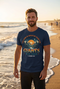 White man wearing The Lord Is Greater Than the Giants You Face Tee at ocean sunset